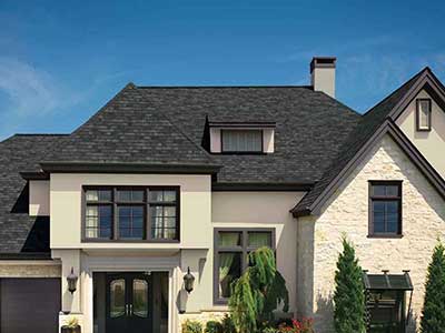 Beige home with a black shingle roof